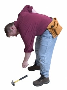 A man bending down to pick up a hammer incorrectly